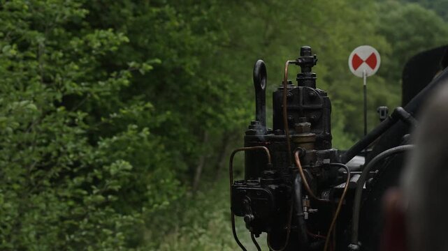 Close up of mechanical steaming details, wheels and pistons of a vintage steam engine in motion. Historic locomotive during the ride, industrial heritage, 4K, ProRes, 50fps.