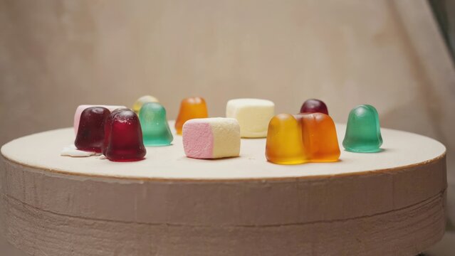 Colorful gummy candies arranged on a round surface against a neutral backdrop