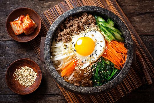Authentic Korean national cuisine presented in a food photograph featuring bibimbap, kimbap, tteokbokki, grilled meat, and an array of banchan including kimchi and jorim.