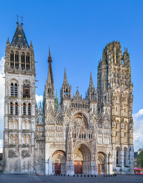 Rouen Cathedral, France, low angle view of main facade. High gothic stone architecture and portals under partly cloudy sky