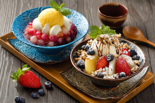 A close-up food photograph of a popular Asian frozen dessert bowl featuring vanilla ice cream and passion fruit sorbet, generously topped with fresh strawberries, blueberries, 