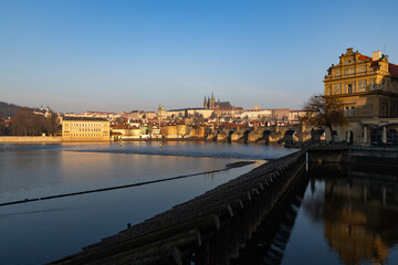 Obraz premium scenic view of Prague Castle and Charles Bridge glowing in golden light over the Vltava River