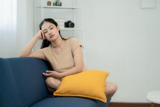Asian woman feeling bored and stressed sitting on sofa at home, mental health, loneliness, depression, burnout concept, lifestyle fatigue, emotional problem, modern life stress
