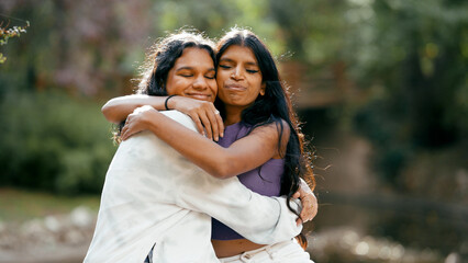 Obraz premium Two young indian women hugging passionately outdoors, expressing warmth and belonging. Celebrating friendship, togetherness, and happiness