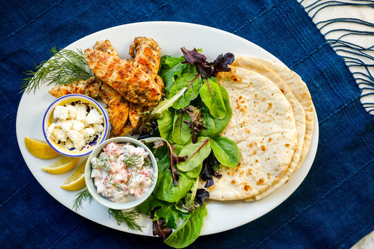 Grilled Greek chicken pitas with salad and lemon