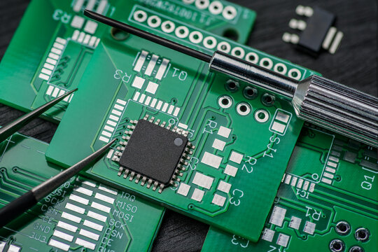 Micro chip IC on printed circuit board PCB with screwdriver and tweezers.