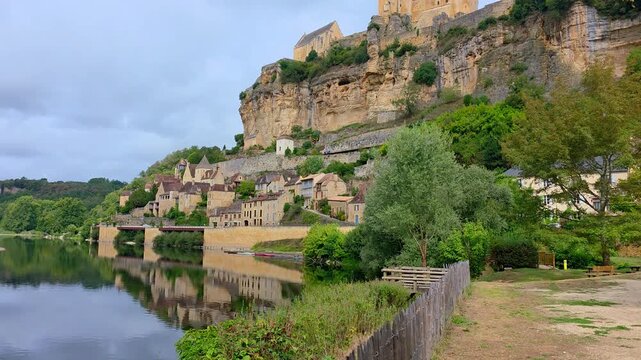 Beautiful French village and castle of Beynac-et-Cazenac and the Dordogne River from the river side park during summer. Slow walking motion.