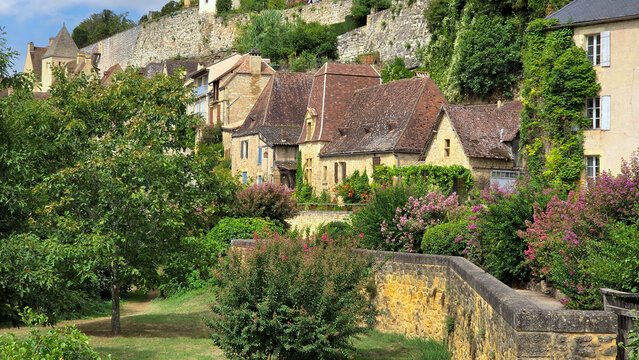 View to the village of Beynac-et-Cazenac, Dordogne, France with flowering shrubs from the river side walkway during summer
