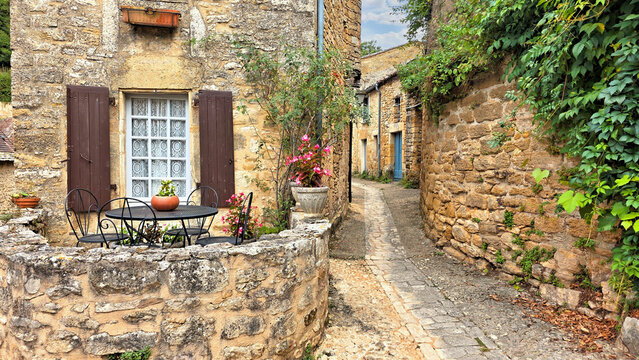 Narrow cobblestone street in the village of Beynac-et-Cazenac, Dordogne, France with medieval stone walls