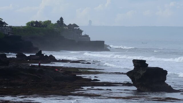 Oceanfront Sacred Site Exploration. Excursion To Holy Site Amid Crashing Waves And Dark Skies. Exploring Revered Religious Landmark Situated Along Tumultuous Ocean Shoreline Tanah Lot, Bali