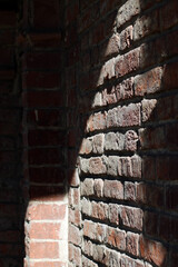 Naklejka premium Old brick wall of building in rays of the sun.