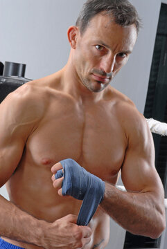 Male boxer or athlete preparing for training or a competition by wrapping his hands with blue hand wraps. This process is a fundamental part of combat sports, such as boxing and M
