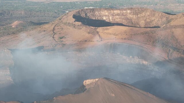 A view shows the inside of a volcano crater in Nicaragua during sunrise. Smoke rises from the crater as the sun lights up the landscape.
