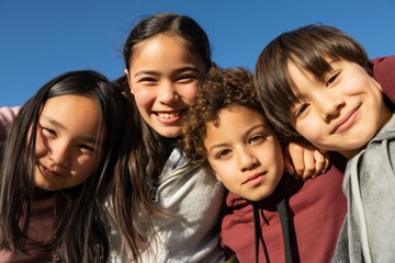 Fototapeta premium Group of children smiling together under clear blue sky