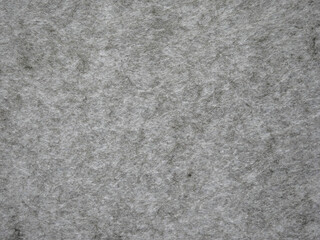 Fototapeta premium Macro close-up of a light gray melange felt fabric sheet with visible fibrous texture and subtle dark fiber flecks. The mottled, heathered surface gives a natural, organic quality ideal for neutral te