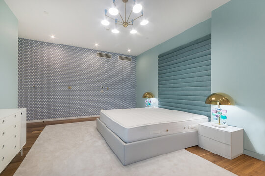 A bedroom shows a clean floor plan with a large bed and simple nightstands. The walls have a unique design. Soft lighting gives a warm feel to the room