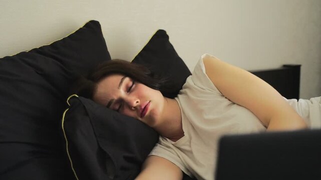 Young woman sleeping next to her laptop computer at home