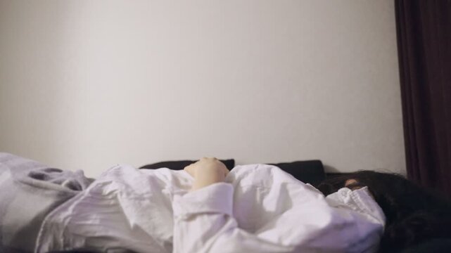 Exhausted young woman falling down on bed while feeling tired