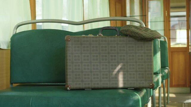 Vintage suitcase and cap resting on a vintage train seat with sunlight streaming in