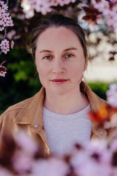 Middle aged woman face portrait between blossom branches direct gaze