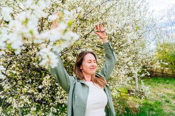 Free relaxed midlife woman enjoying spring blossom with eyes closed