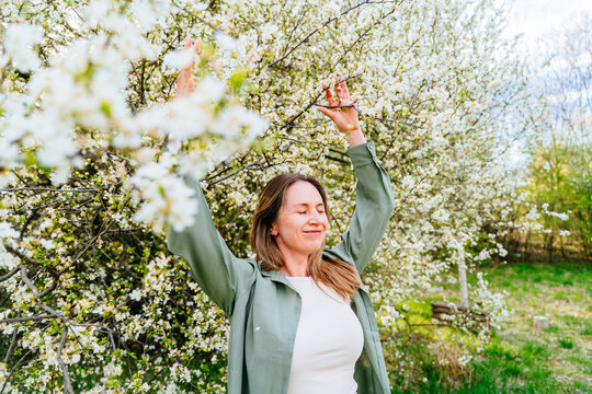 Free relaxed midlife woman enjoying spring blossom with eyes closed