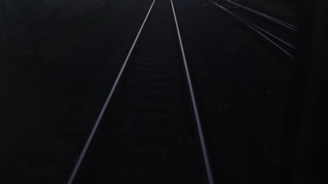 Railway tracks diverge into split path with smooth motion blur in low light creating sense of decision direction change and fast transition