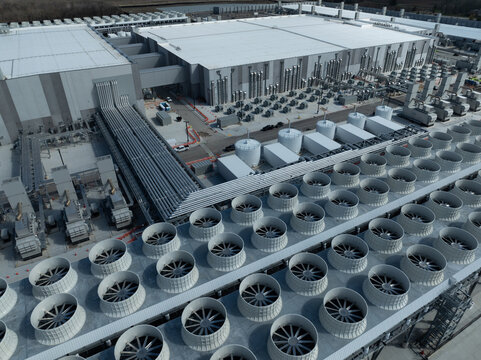 Aerial close-up of an AI data center showing large-scale cooling fans, pipelines, and industrial infrastructure powering high-performance computing operations.
