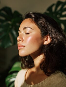 Young Woman Enjoying Peaceful Moment in Sunlight with Eyes Closed Indoors