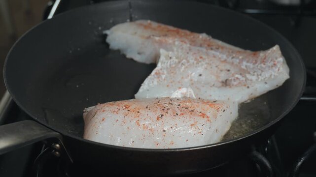Searing white fish fillets in a hot skillet