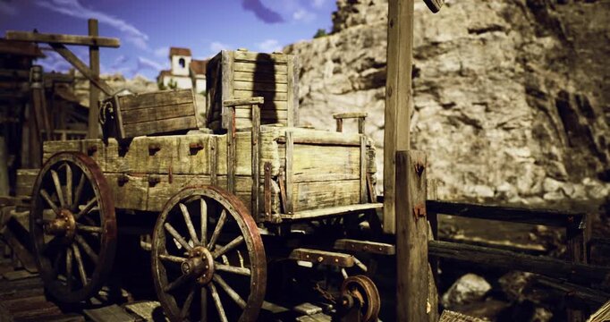 A weathered wooden wagon rests on a dock, surrounded by rocky cliffs. The sun illuminates the scene, highlighting the rustic details of the wagon and its surroundings.