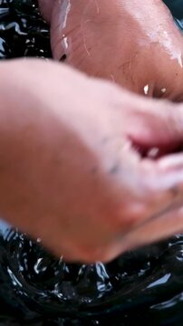 Squid cleaning and preparation by hand with ink release washing in blue basin and draining in yellow colander showing traditional Asian seafood process