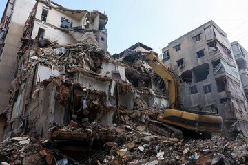 Fototapeta premium Southern Suburbs - April 10 2026: Heavy machinery work at the site of an Israeli strike carried out in southern suburbs of Beirut Lebanon showing excavation equipment clearing rubble and debris
