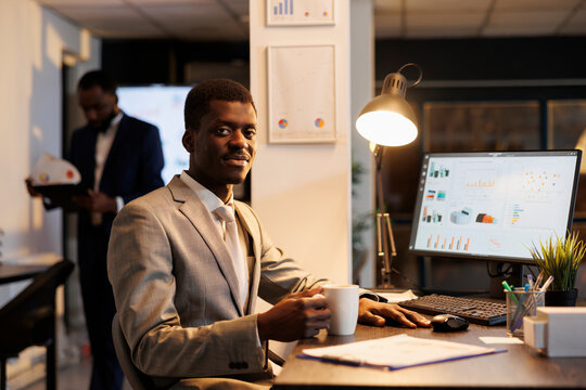 Businessman standing at desk table analyzing company statistics, working at financial growth report before start preparing investment strategy. Entrepreneur working late at night in startup office