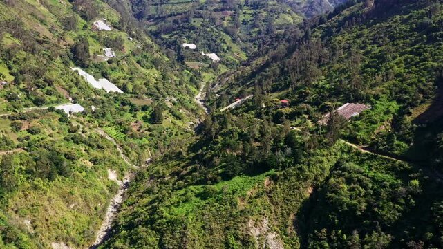 Aerial view of a mountain stream with the hills alongside covered in agricultural fields and greenhouses