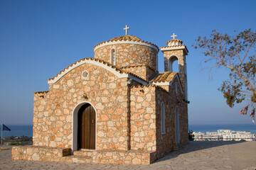 Fototapeta premium Church of Profitis Elias in Protaras Cyprus. Traditional Orthodox stone church with dome and bell tower under blue sky. Mediterranean architecture and travel destination in Cyprus.