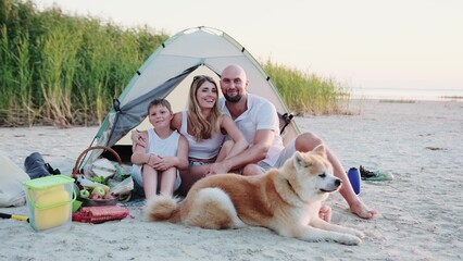 Happy family sitting in the tent on the beach with Akita Inu © Vlad