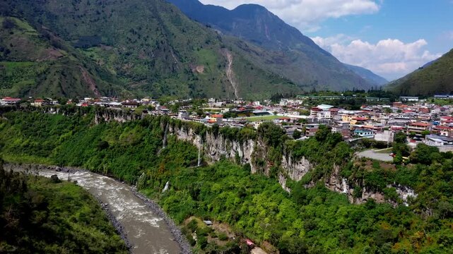 Aerial view over banos with two small waterfalls visible over the cliff separating the village with the Pastaza river