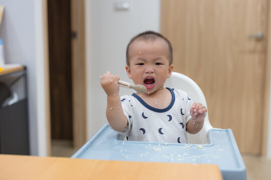 Toddler enjoying messy rice meal on high chair