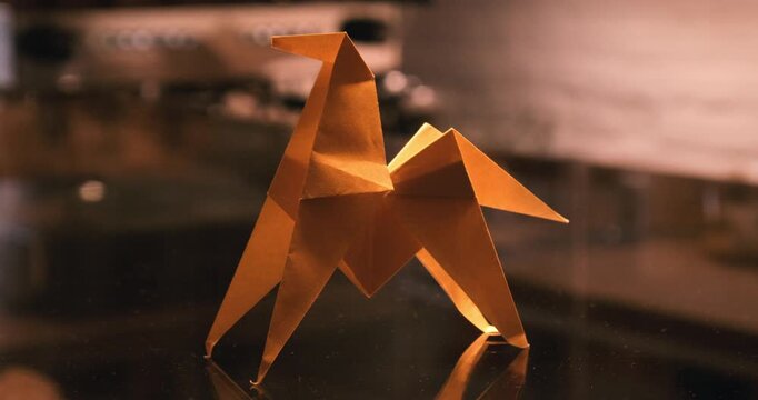 Yellow Origami Crane on Wooden Table Next to Coffee in a Bakery Cafe