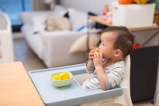 Little boy eating corn at home dining table