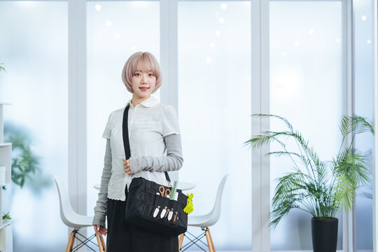 ヘアメイク道具を持つハイトーンヘアの女性スタッフ