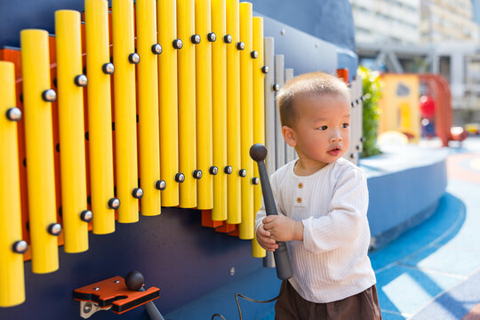 Little boy playing metallophone instrument at outdoor park