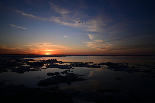 Spring scene of a sun set over a calm lake as pieces of broken ice float along the surface of the water