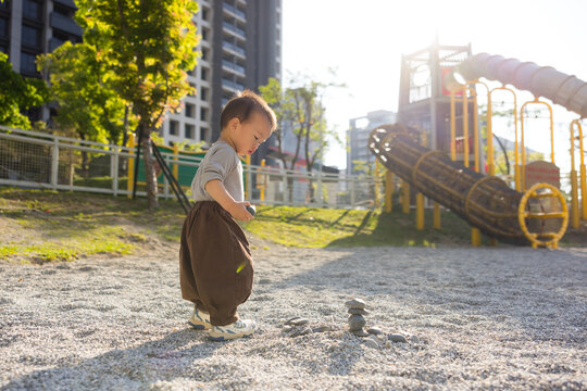 Cute baby exploring stone on park ground