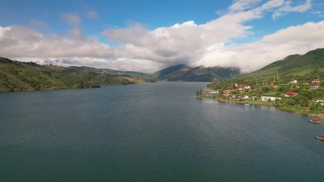 Aerial view of lake amidst green mountains and clouds