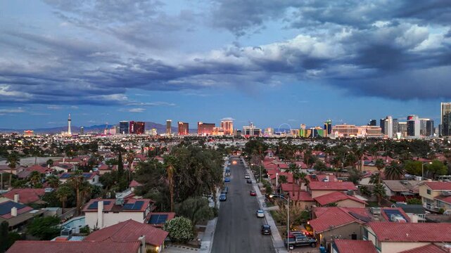 Aerial drone view flying forward over a Las Vegas suburban neighborhood at dusk with the Strip skyline in the background