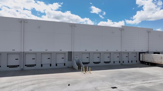 Drone Orbit Shot Left to Right of Commercial Warehouse Loading Dock with Shipping Container.