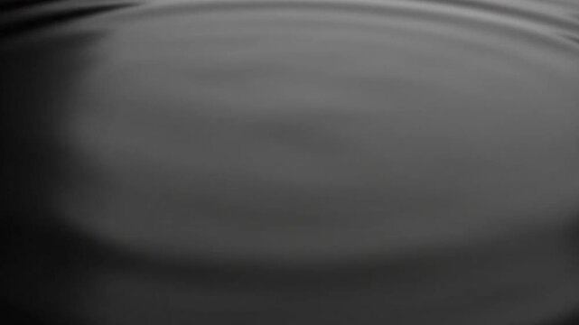 A close-up shot of dark liquid with concentric ripples creating a circular pattern effect