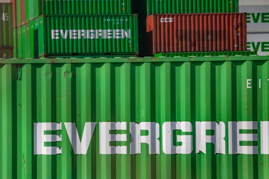 Evergreen shipping containers stacked in a busy cargo yard at an international port